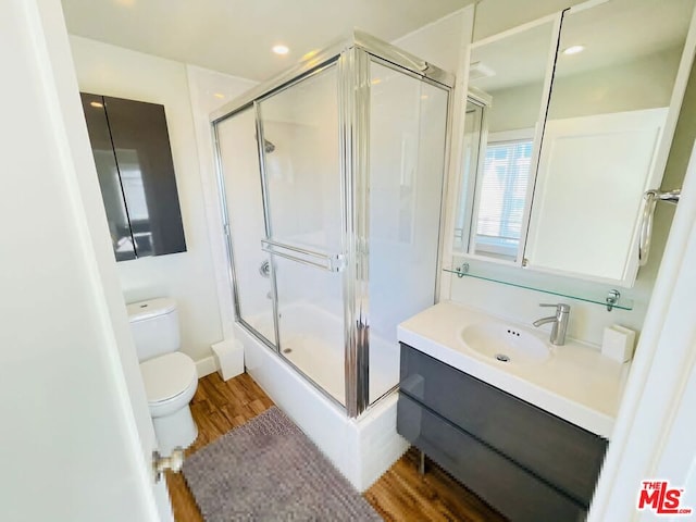 full bathroom with enclosed tub / shower combo, hardwood / wood-style floors, toilet, and vanity