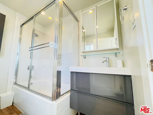 bathroom with enclosed tub / shower combo, hardwood / wood-style floors, and vanity