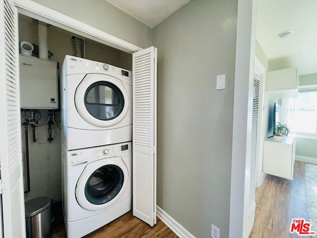 laundry area featuring water heater, stacked washer and clothes dryer, and hardwood / wood-style flooring