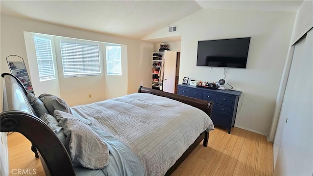 bedroom featuring lofted ceiling, light wood-type flooring, and a closet