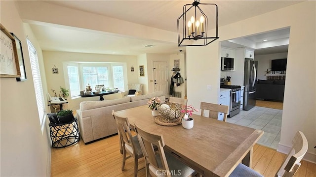 dining room with light wood-type flooring and an inviting chandelier