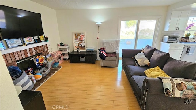 living room with a brick fireplace and light hardwood / wood-style flooring