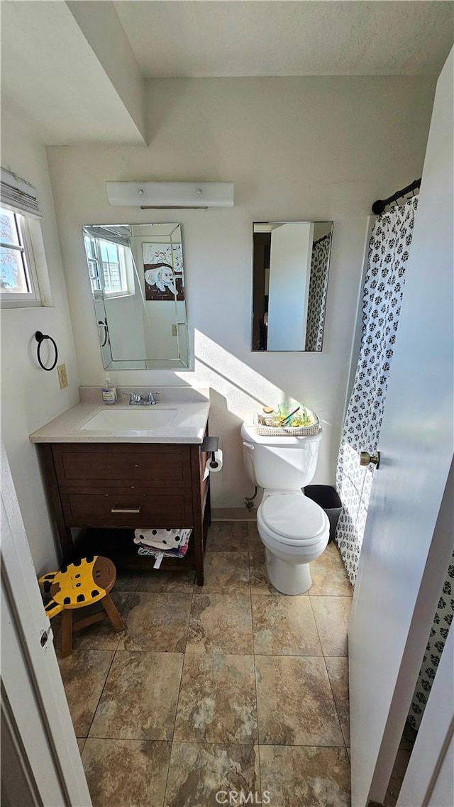 bathroom featuring toilet, a healthy amount of sunlight, and vanity