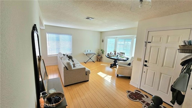 workout area featuring a textured ceiling and light hardwood / wood-style flooring