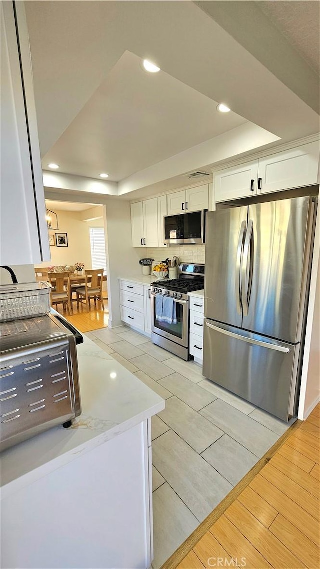 kitchen featuring appliances with stainless steel finishes, a tray ceiling, and white cabinetry