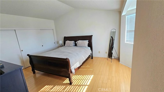 bedroom with a closet, lofted ceiling, and light wood-type flooring