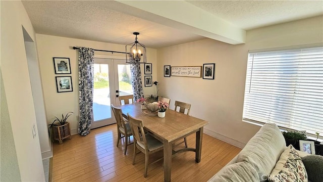 dining room with a healthy amount of sunlight, a textured ceiling, and light hardwood / wood-style flooring