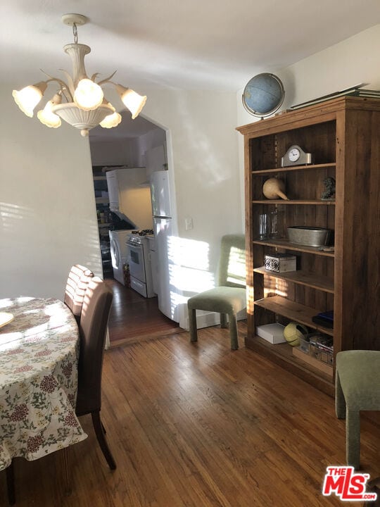 dining space with dark hardwood / wood-style floors and a notable chandelier