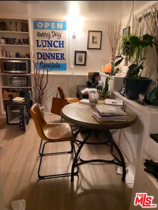 dining space with built in shelves and hardwood / wood-style floors