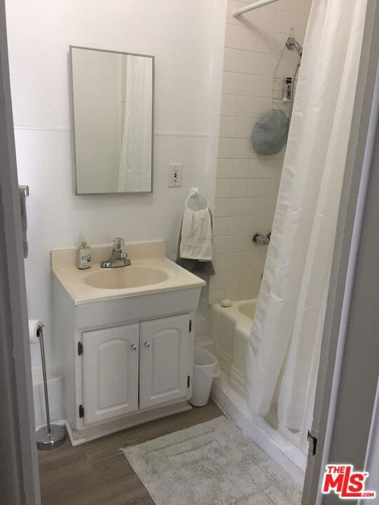 bathroom featuring hardwood / wood-style flooring, vanity, and shower / bath combination with curtain