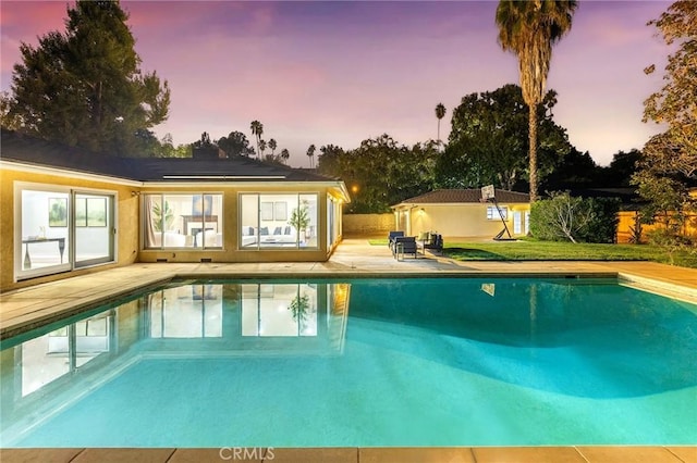 pool at dusk featuring a patio