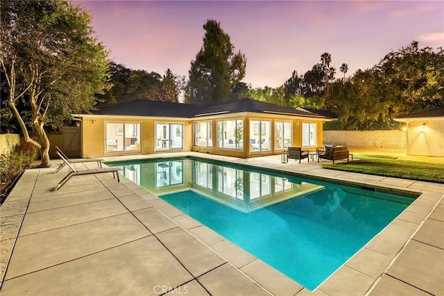 pool at dusk featuring a patio area