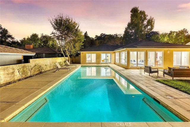 pool at dusk featuring an outdoor hangout area and a patio