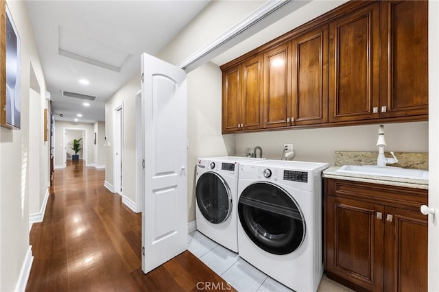 clothes washing area with cabinets, independent washer and dryer, and light hardwood / wood-style flooring