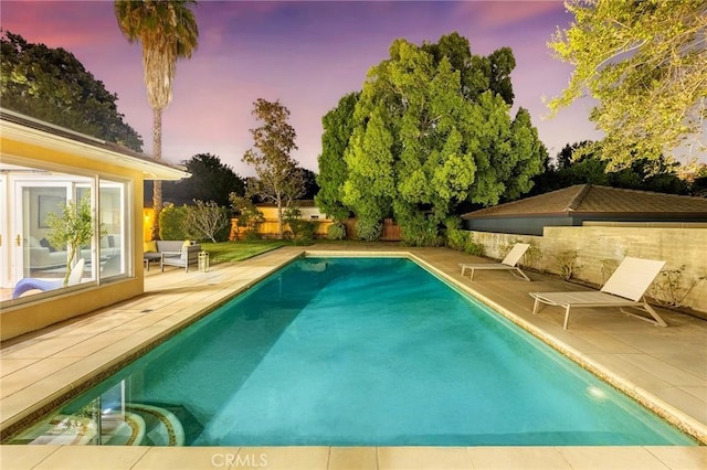 pool at dusk featuring a patio