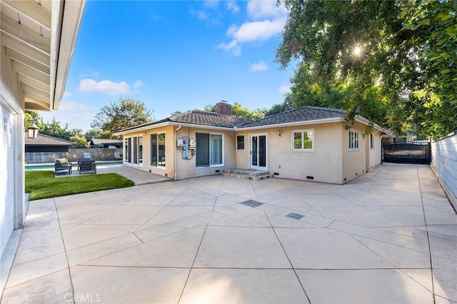 rear view of house featuring a swimming pool and a patio