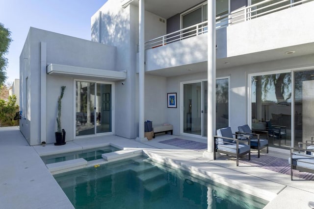 back of house with a pool with hot tub, a balcony, and a patio