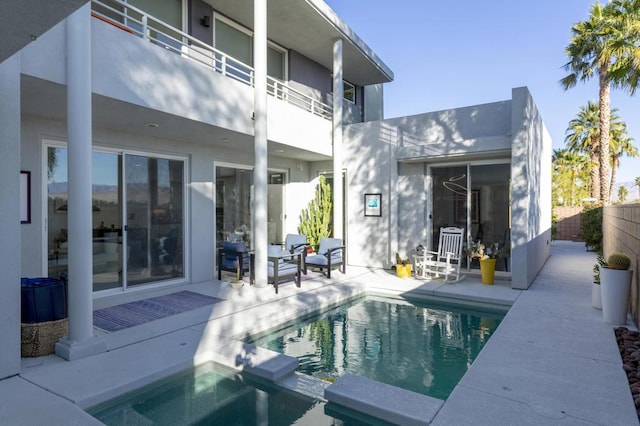 rear view of house featuring a fenced in pool, a patio area, and a balcony