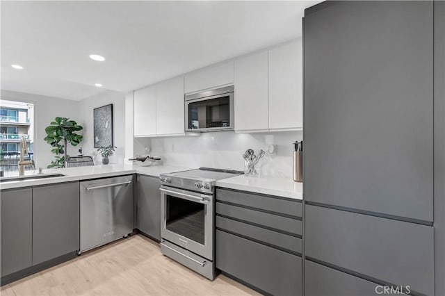 kitchen featuring stainless steel appliances, white cabinetry, and gray cabinets