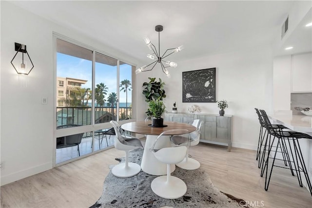 dining space with light wood-type flooring, a notable chandelier, and floor to ceiling windows