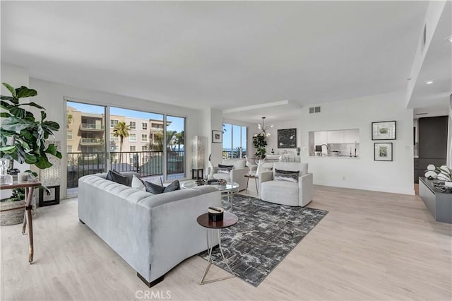 living room with light hardwood / wood-style floors and a notable chandelier