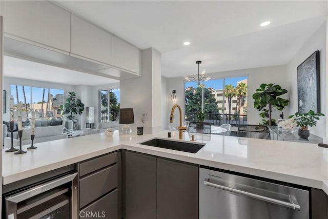 kitchen with an inviting chandelier, gray cabinetry, wine cooler, stainless steel dishwasher, and sink