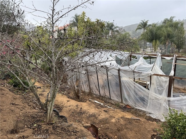 exterior space with a greenhouse, a mountain view, and an outbuilding