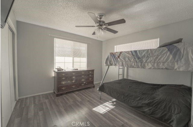 bedroom with a textured ceiling, ceiling fan, and dark hardwood / wood-style floors