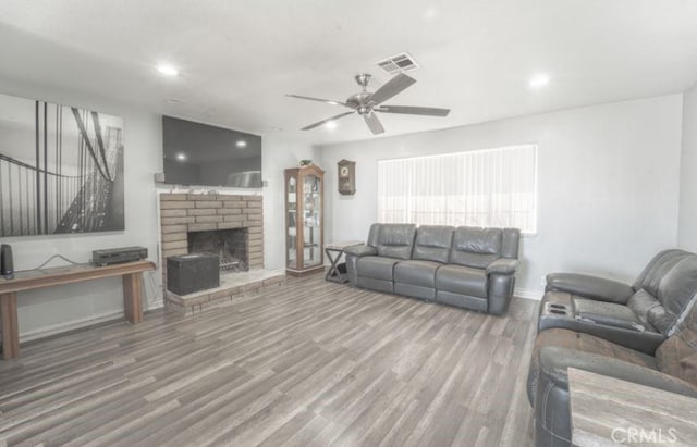 living room with ceiling fan, a fireplace, and hardwood / wood-style flooring