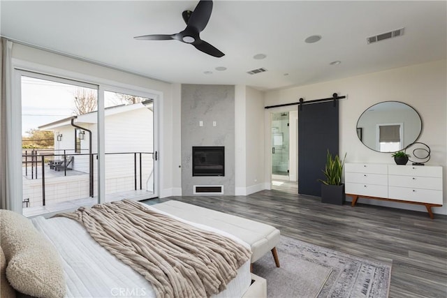 bedroom with a fireplace, dark hardwood / wood-style flooring, access to outside, ceiling fan, and a barn door