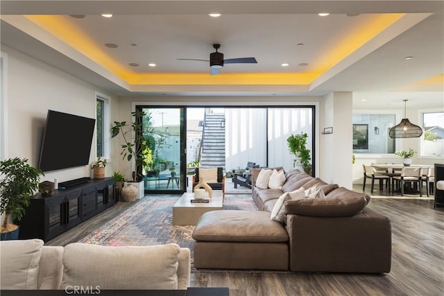 living room featuring ceiling fan, a tray ceiling, and hardwood / wood-style floors