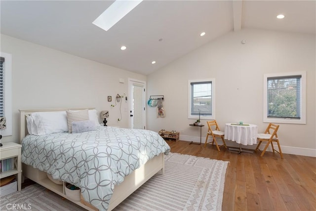 bedroom with beamed ceiling, high vaulted ceiling, light wood-type flooring, and a skylight