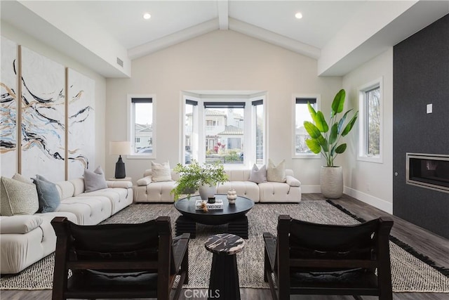 living room featuring a wealth of natural light, vaulted ceiling, a large fireplace, and hardwood / wood-style floors