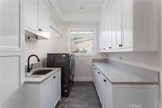 laundry area featuring dark hardwood / wood-style flooring, sink, cabinets, and washer and dryer