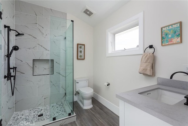 bathroom featuring vanity, a tile shower, hardwood / wood-style floors, and toilet