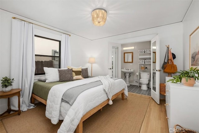 bedroom featuring ensuite bathroom, sink, and light hardwood / wood-style flooring