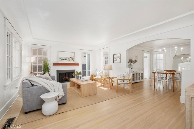 living room with plenty of natural light, a notable chandelier, and light hardwood / wood-style flooring