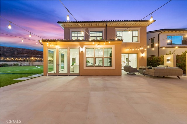 back house at dusk featuring a patio and an outdoor hangout area