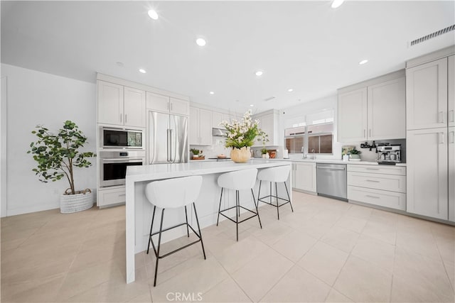 kitchen with a kitchen island, white cabinetry, sink, a kitchen bar, and black appliances