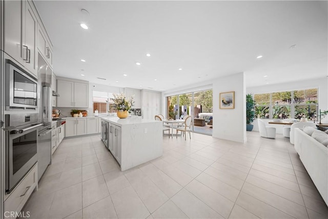 kitchen featuring white cabinetry, stainless steel appliances, a center island, and light tile patterned flooring