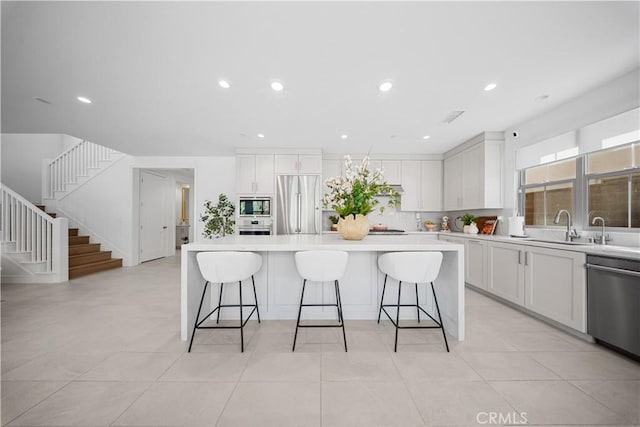 kitchen featuring a kitchen island, a breakfast bar, built in appliances, and white cabinets