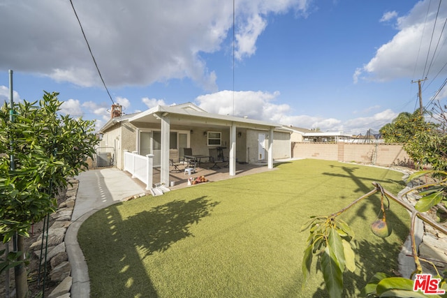 back of house with a patio area and a lawn