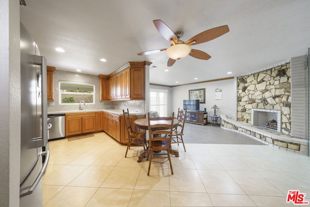 kitchen featuring stainless steel appliances, a fireplace, backsplash, ornamental molding, and light tile patterned flooring