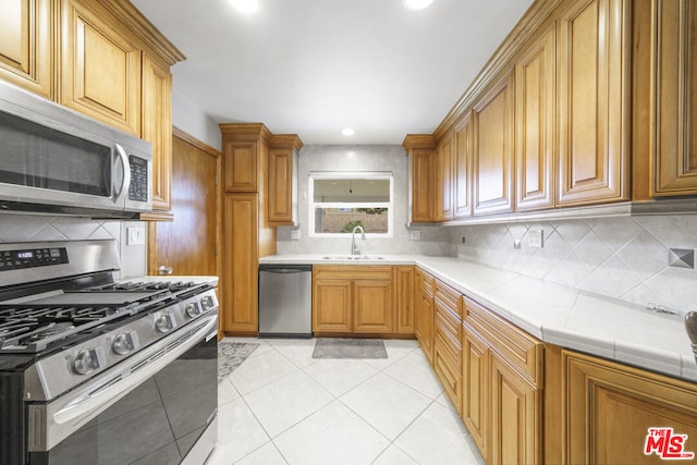 kitchen with sink, decorative backsplash, light tile patterned floors, and stainless steel appliances