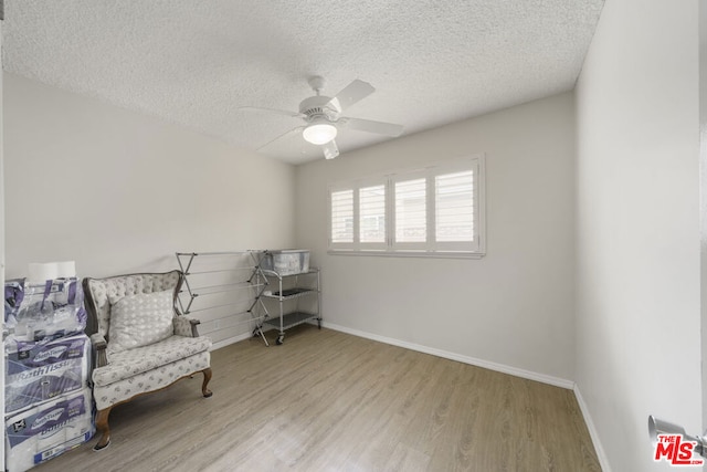 sitting room with light wood-type flooring, a textured ceiling, and ceiling fan