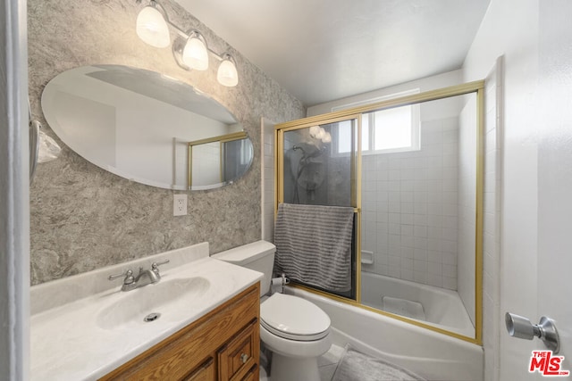 full bathroom with combined bath / shower with glass door, toilet, and vanity