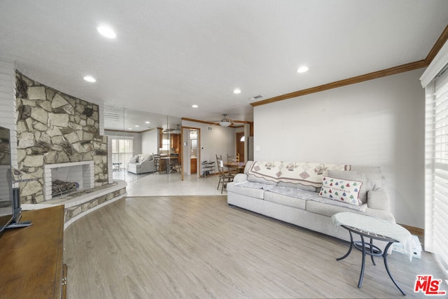 living room featuring ceiling fan, light hardwood / wood-style flooring, a fireplace, and crown molding