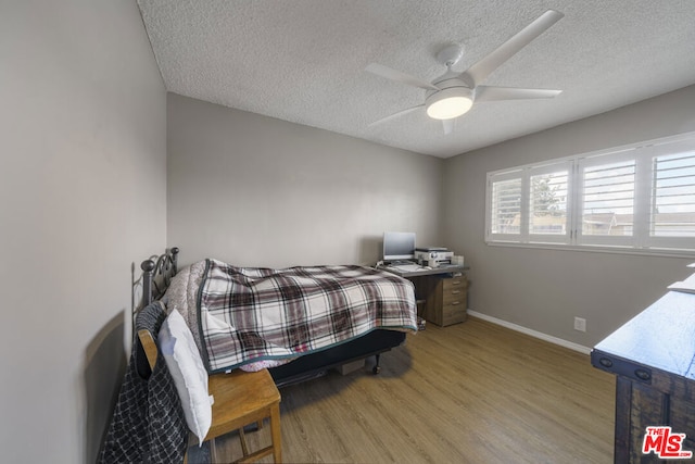 bedroom with light wood-type flooring, ceiling fan, and a textured ceiling