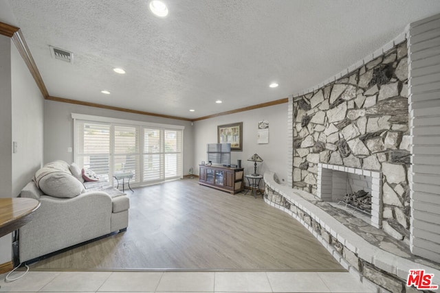 tiled living room featuring a textured ceiling, ornamental molding, and a fireplace