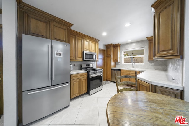 kitchen with sink, light tile patterned flooring, decorative backsplash, and stainless steel appliances